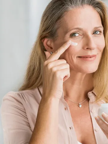 Woman gently applying moisturiser to her cheek